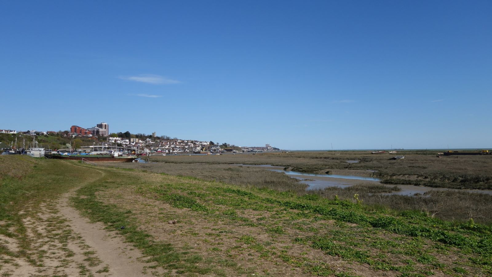 Coastal landscape with marshes, boats and a town in the background